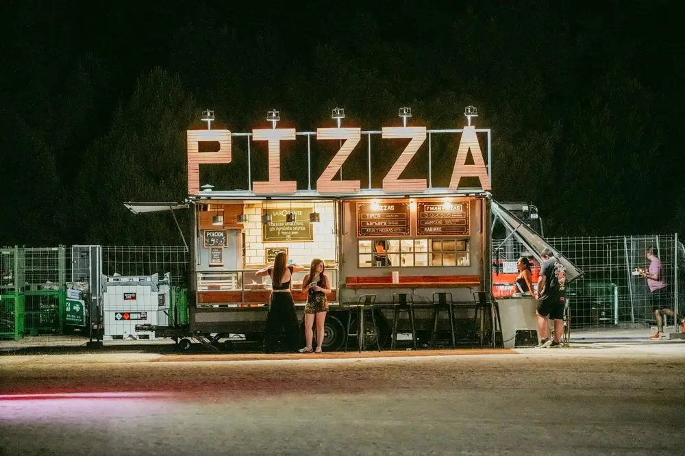 Puesto de pizza con letras luminosas al anochecer